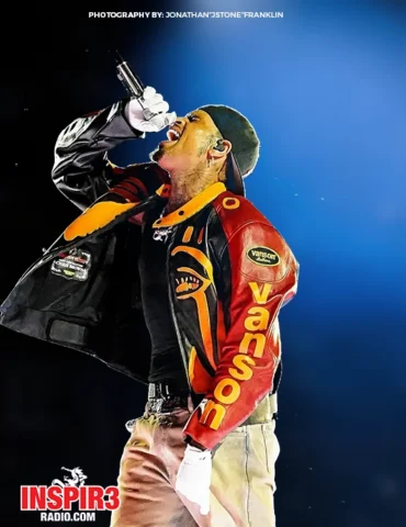 R&B Singer Chris Brown poses in black hat, red, yellow, and red jacket, white pants , and white gloves performing his song on stage at Usher and his R&B tour. Photo by Jstone from Inspir3 Radio.